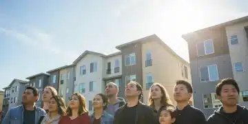 Diverse community looking at new affordable housing complex, symbolizing 2026 housing assistance.